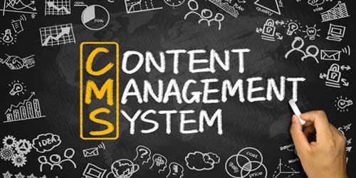 Sort tavle med symboler der omkranser hovedbudskabet "Content Management System". Neders ses en hånd der holder et stykke kridt ved teksten.