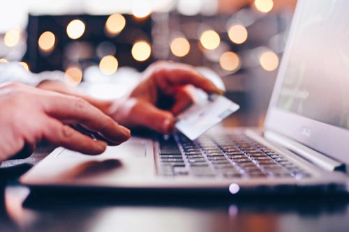 Webshop design. Billedet viser en person der indtaster kreditkortoplysninger på en laptop